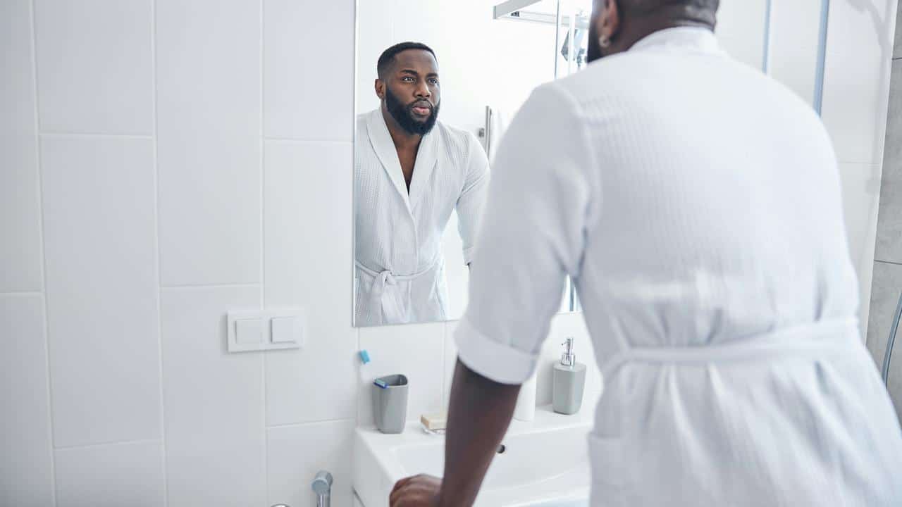 A father looking at himself in the bathroom mirror.