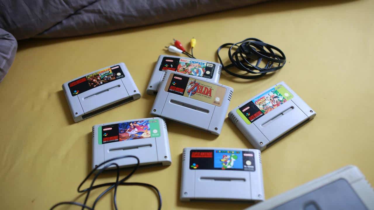 A collection of Super Nintendo game cartridges on a bed.