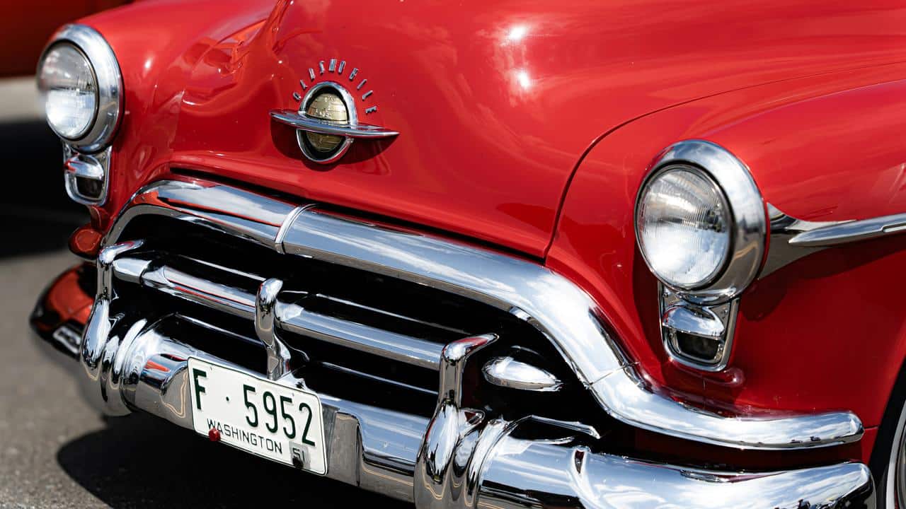A close-up of a red vintage Oldsmobile car front with chrome details.