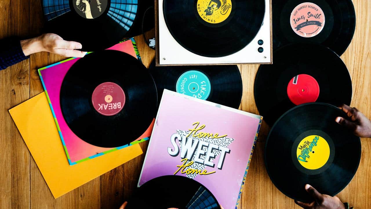 A collection of vinyl records and a turntable on a wooden surface.