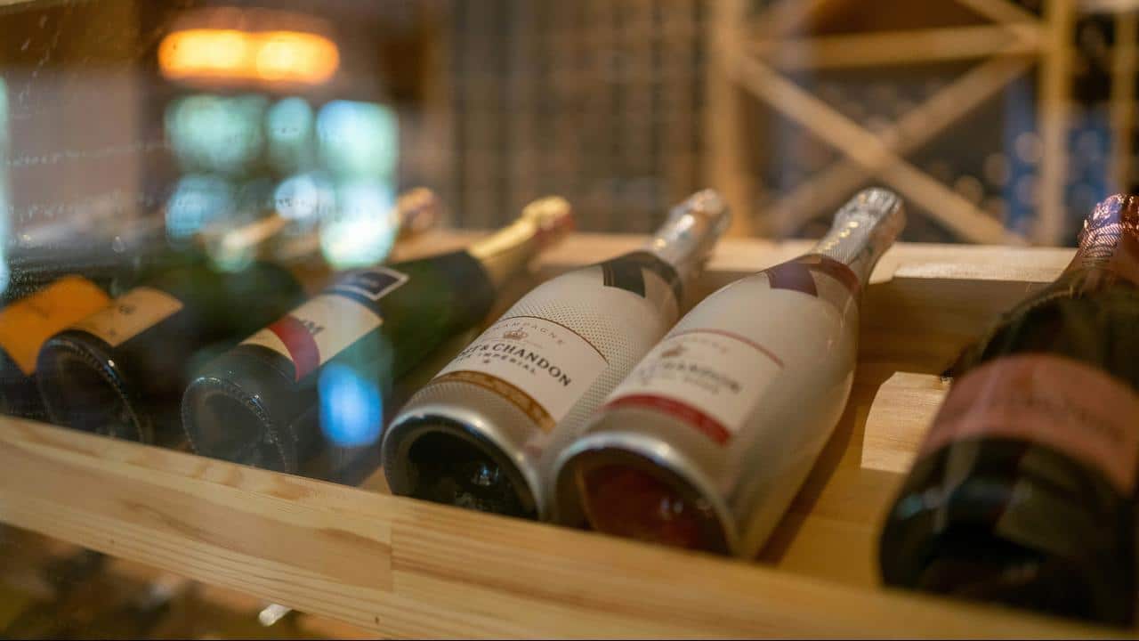 A row of champagne bottles stored in a wooden wine rack.