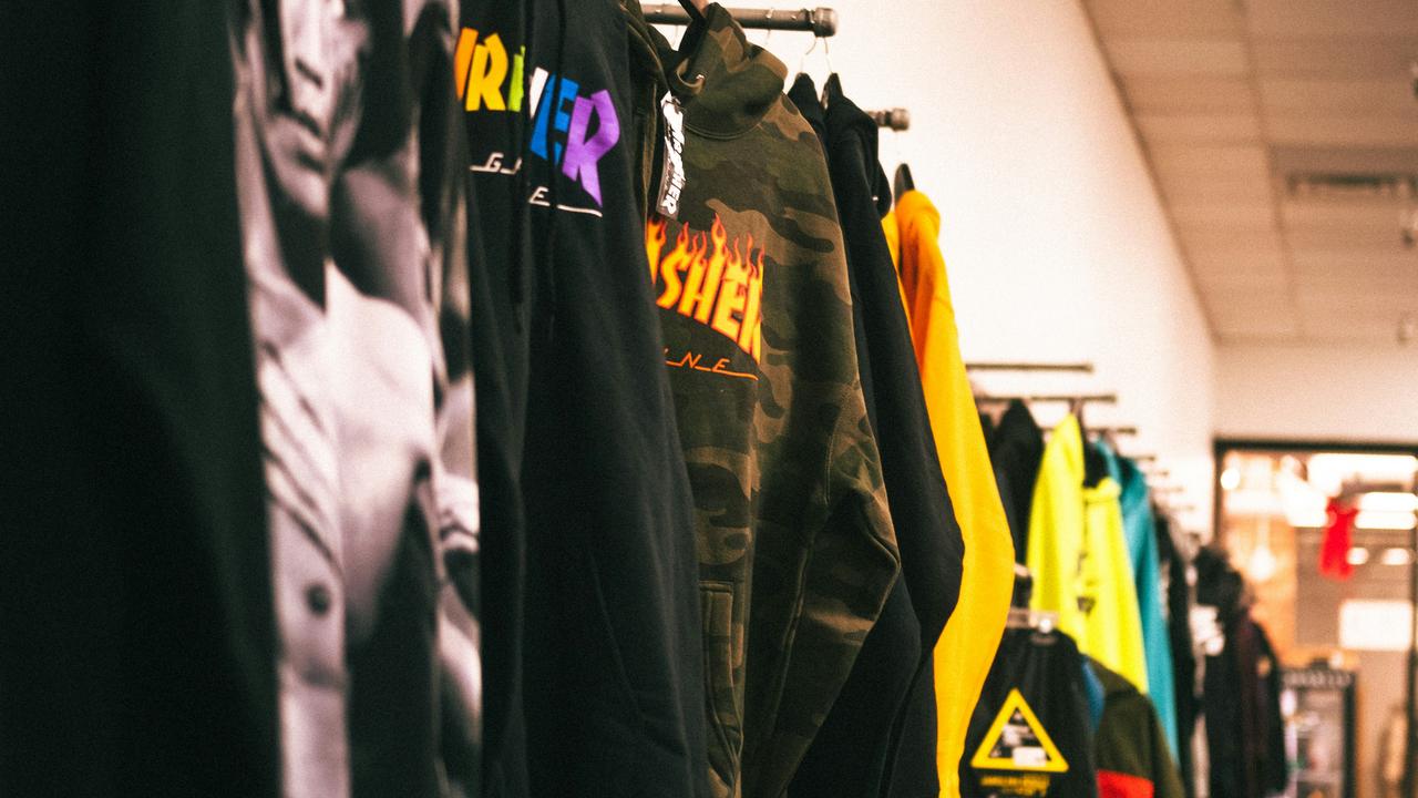 A row of trendy graphic hoodies and jackets hanging on a clothing rack in a retail store.