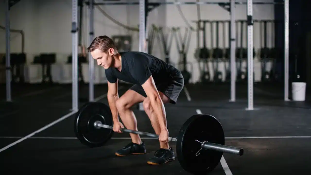 Man lifting weights in a bright fitness studio.