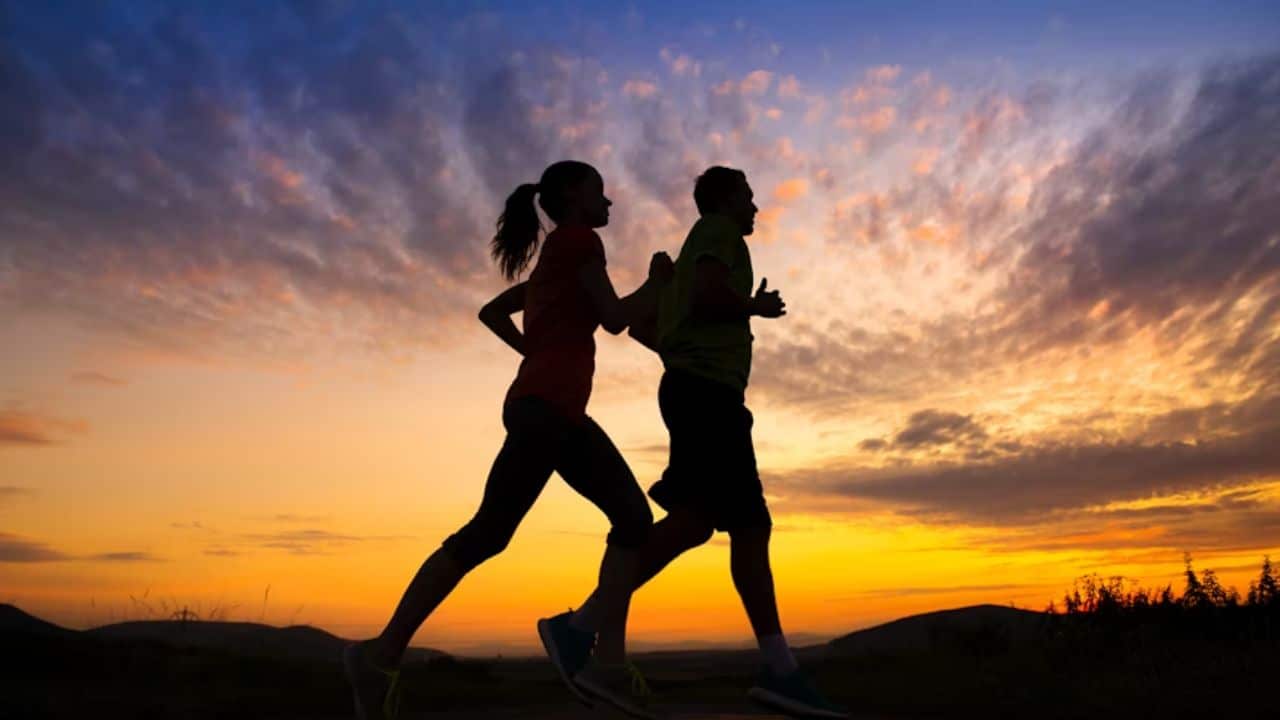 Couple jogging together at sunrise.