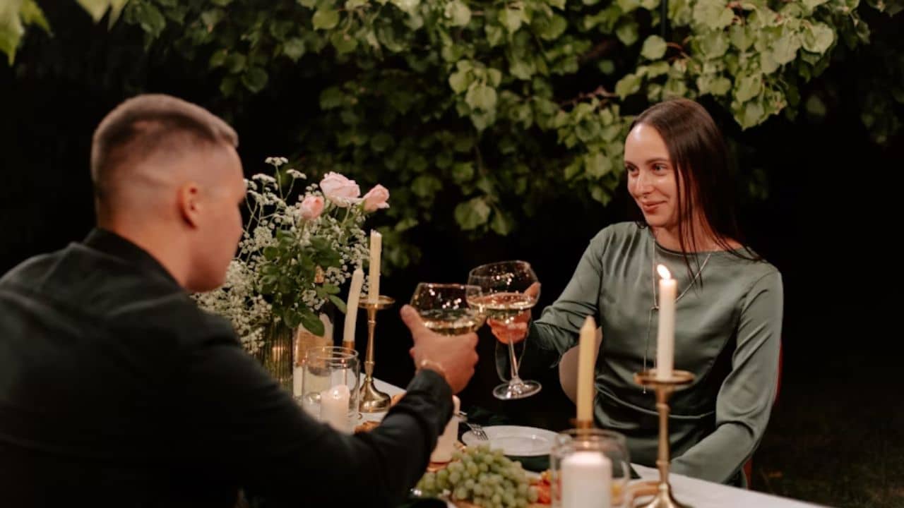 Couple clinking glasses at a candlelit dinner.