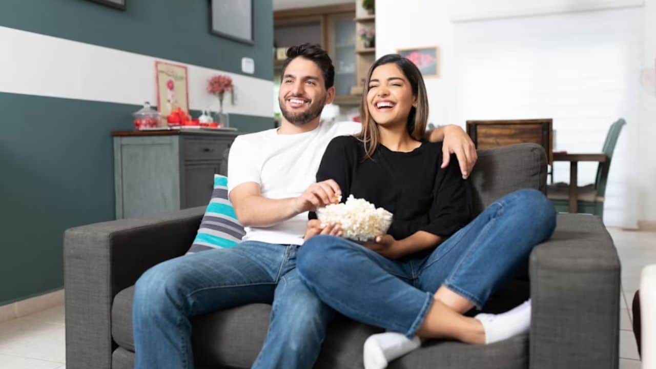 Couple relaxing on a sofa watching TV after a busy day.