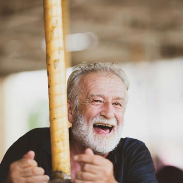 An elderly man laughing on a carousel.