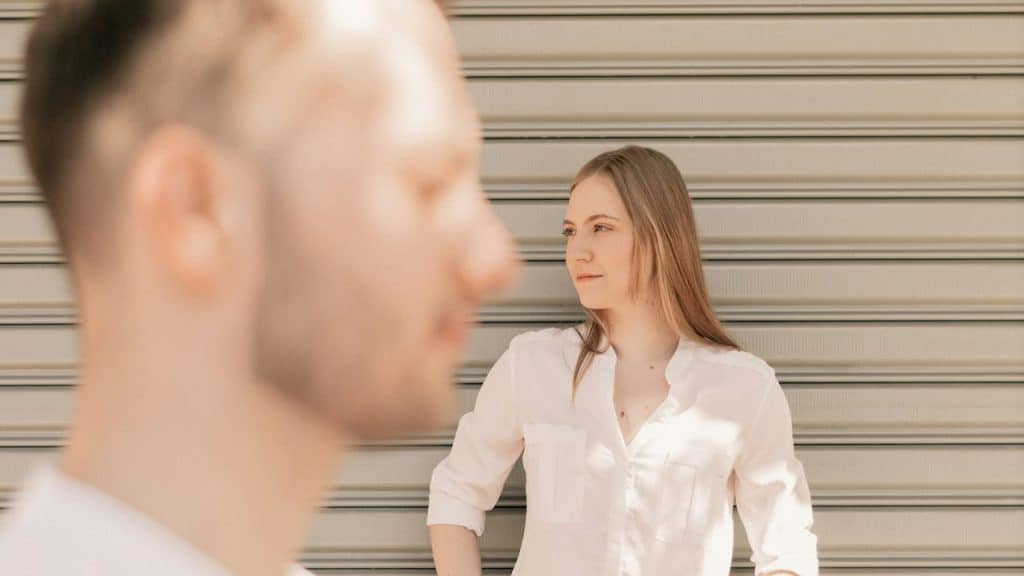 A man's blurry profile is in the foreground while a woman stands behind him.