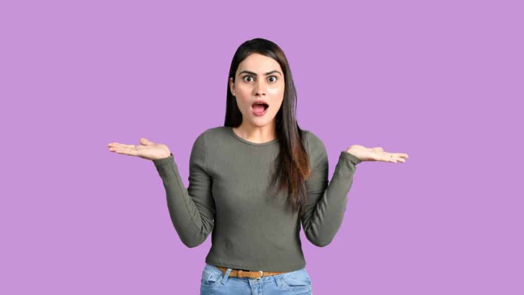 A woman with an astonished expression holds her hands out on a purple background.
