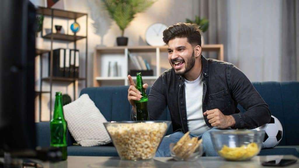 A man excitedly watches television while sitting on a couch.