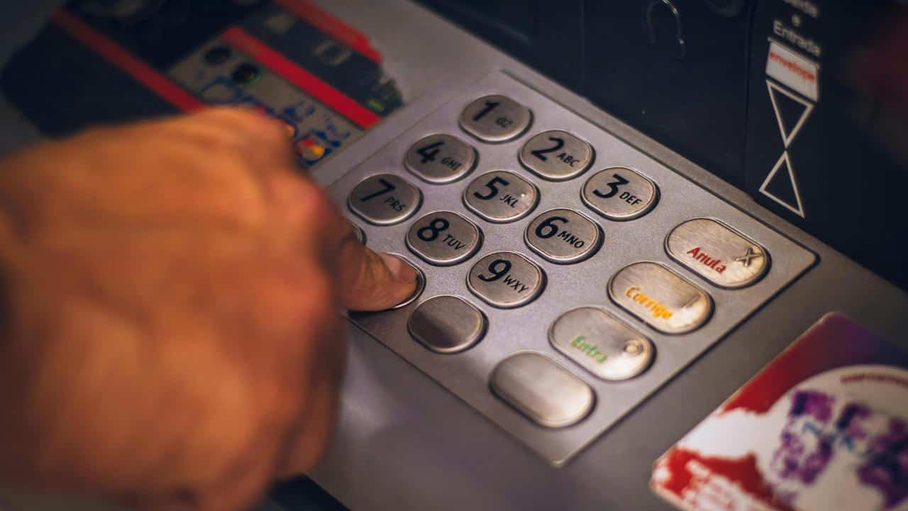 A person pressing a button on an ATM keypad.