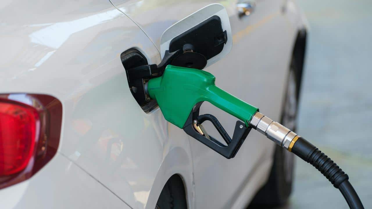 A green fuel nozzle inserted into a car’s gas tank.