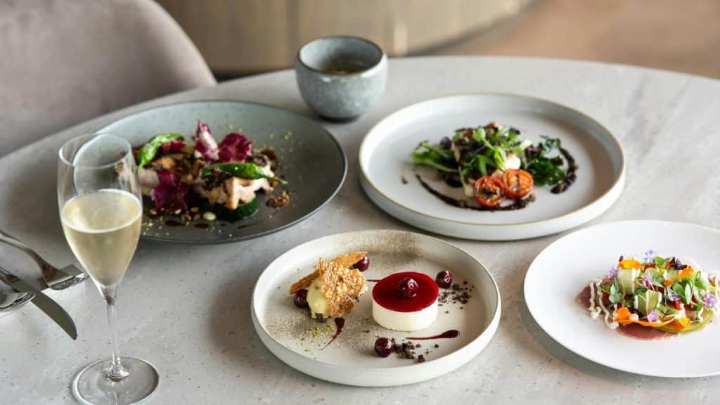 A table with plates of gourmet food and a glass of champagne.