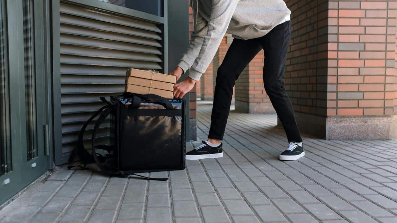 A delivery person placing packages into an insulated bag.