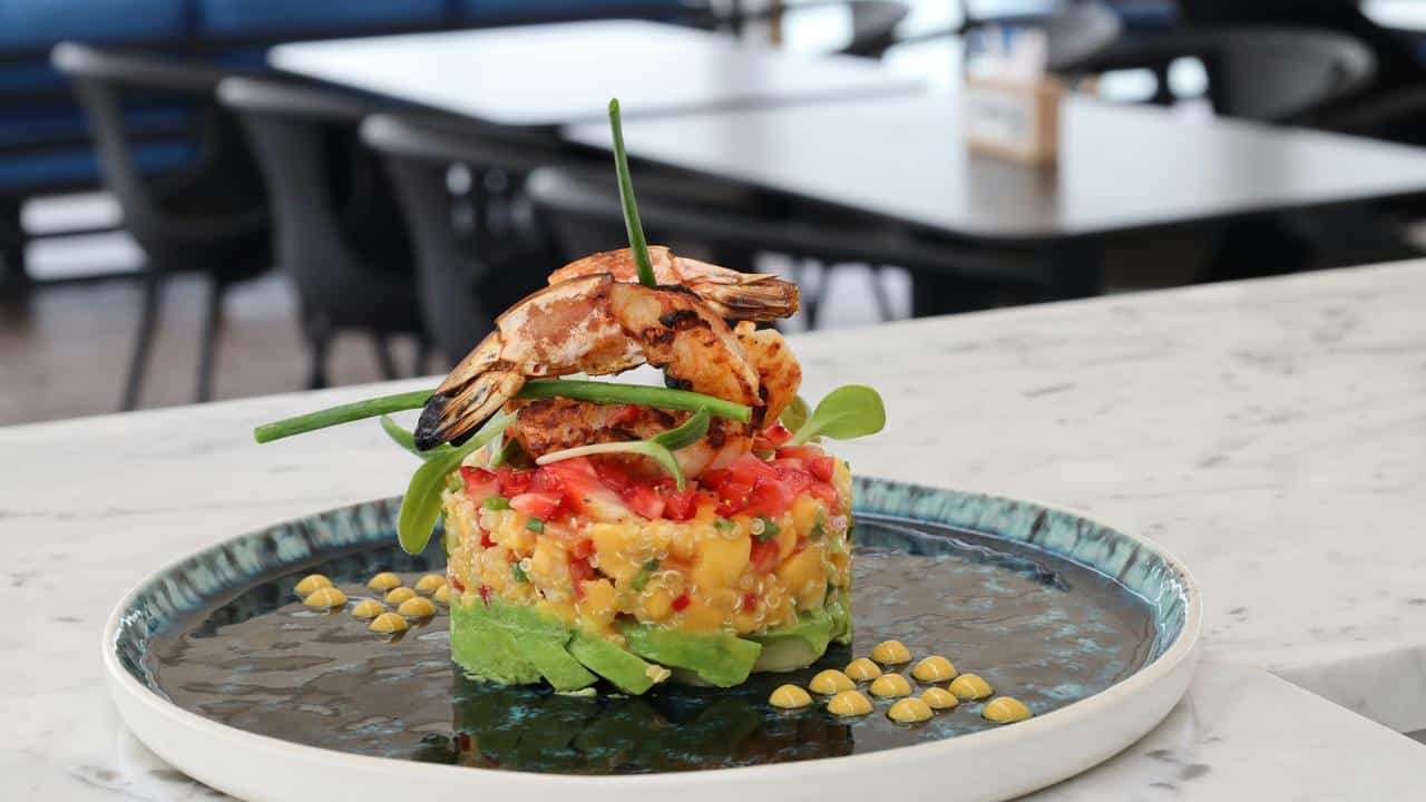 A gourmet dish with grilled shrimp on a bed of diced vegetables.