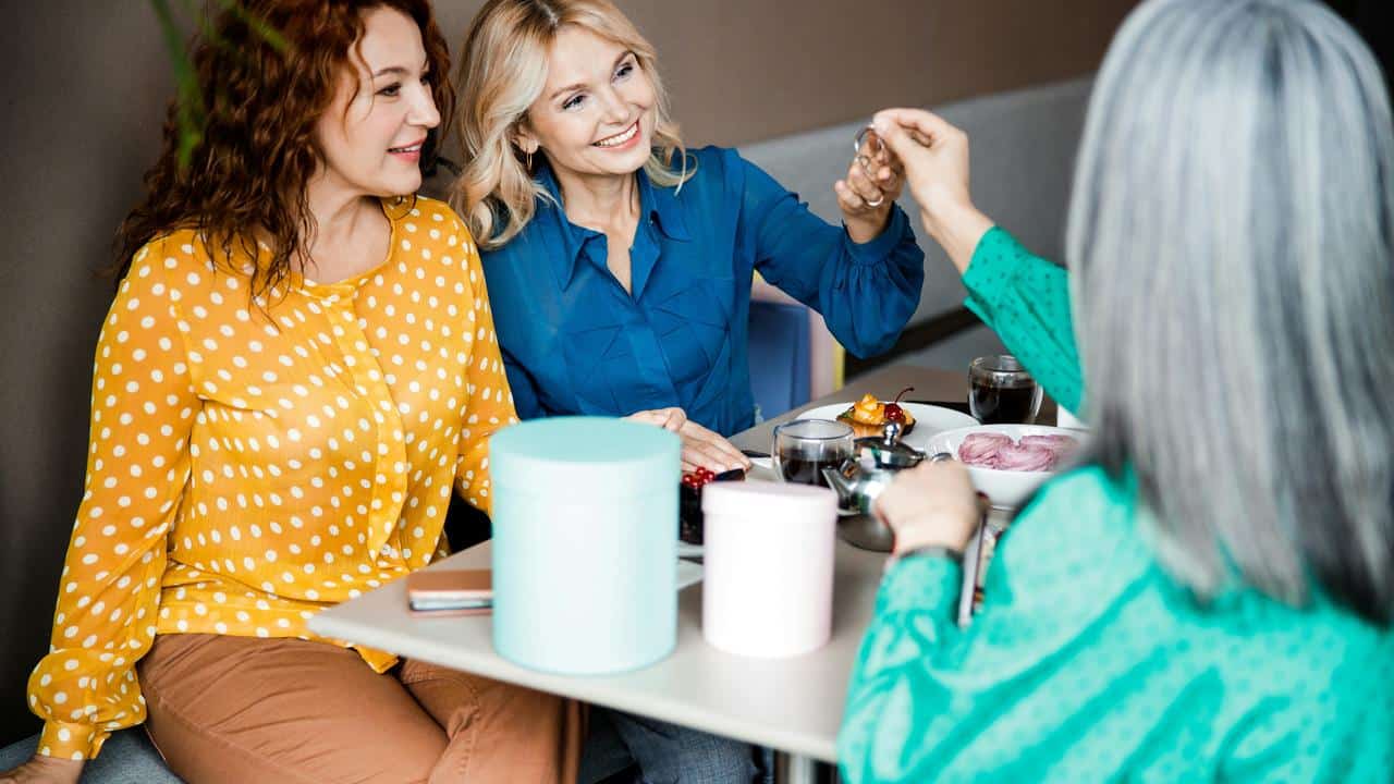 A group of women enjoying food and drinks together at a table.