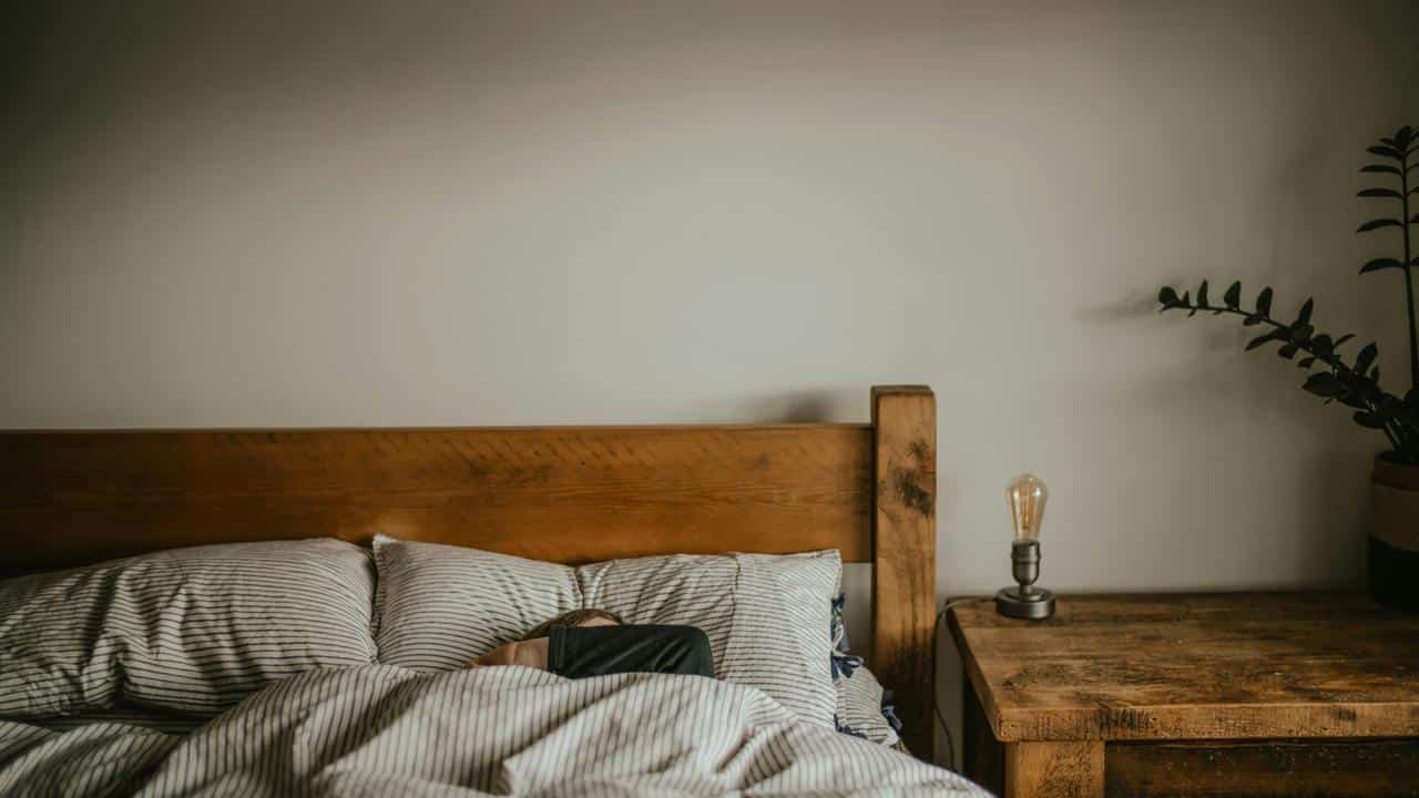 A person sleeping in a bed with striped bedding.