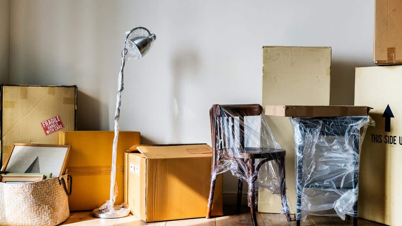 A room filled with moving boxes and wrapped furniture.