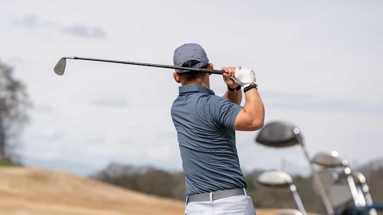 A golfer swinging a club on a golf course.