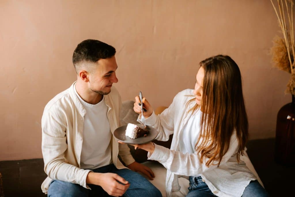 A man and woman sharing with a slice of cake