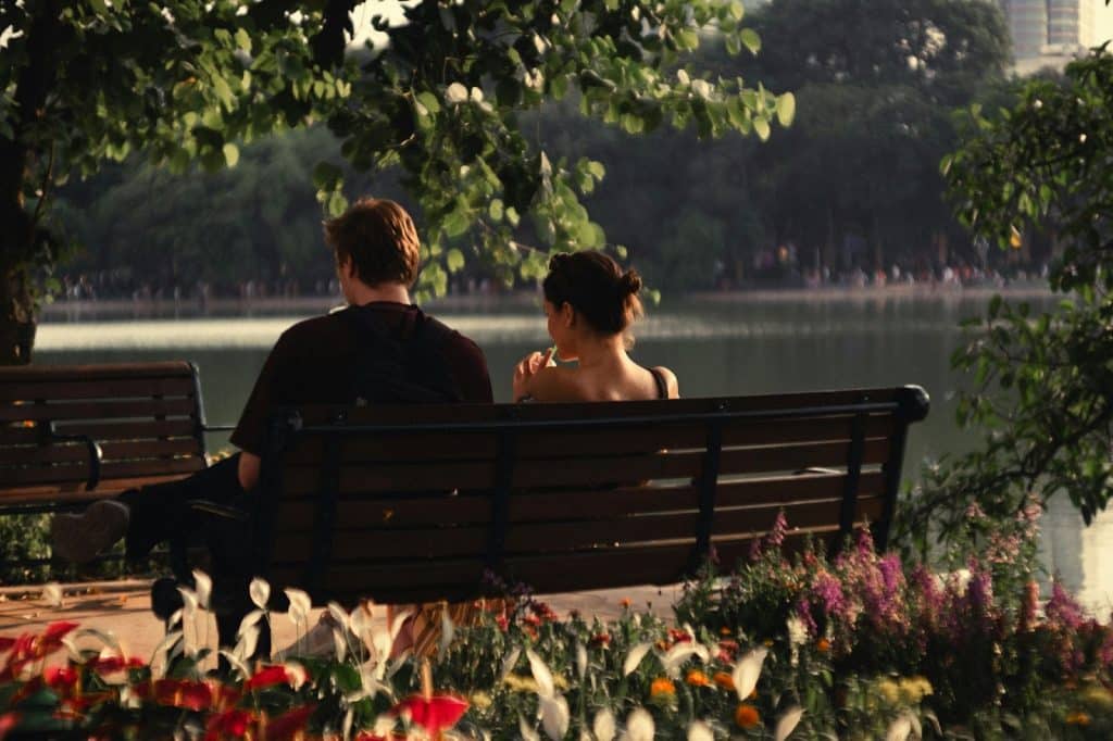 A man and woman sitting at the bench while having a conversation