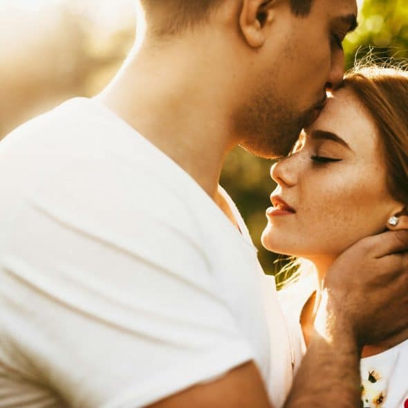 A man kissing a woman’s forehead