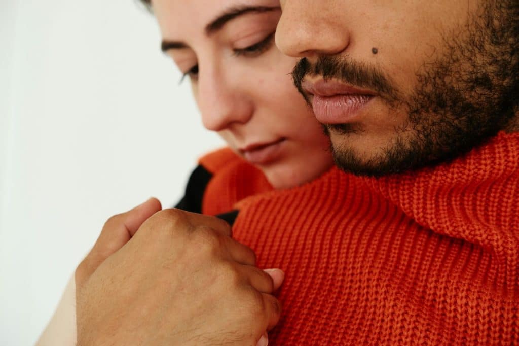 A man being hugged by a woman