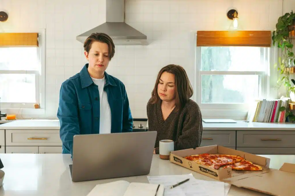 A man and woman working while eating a pizza