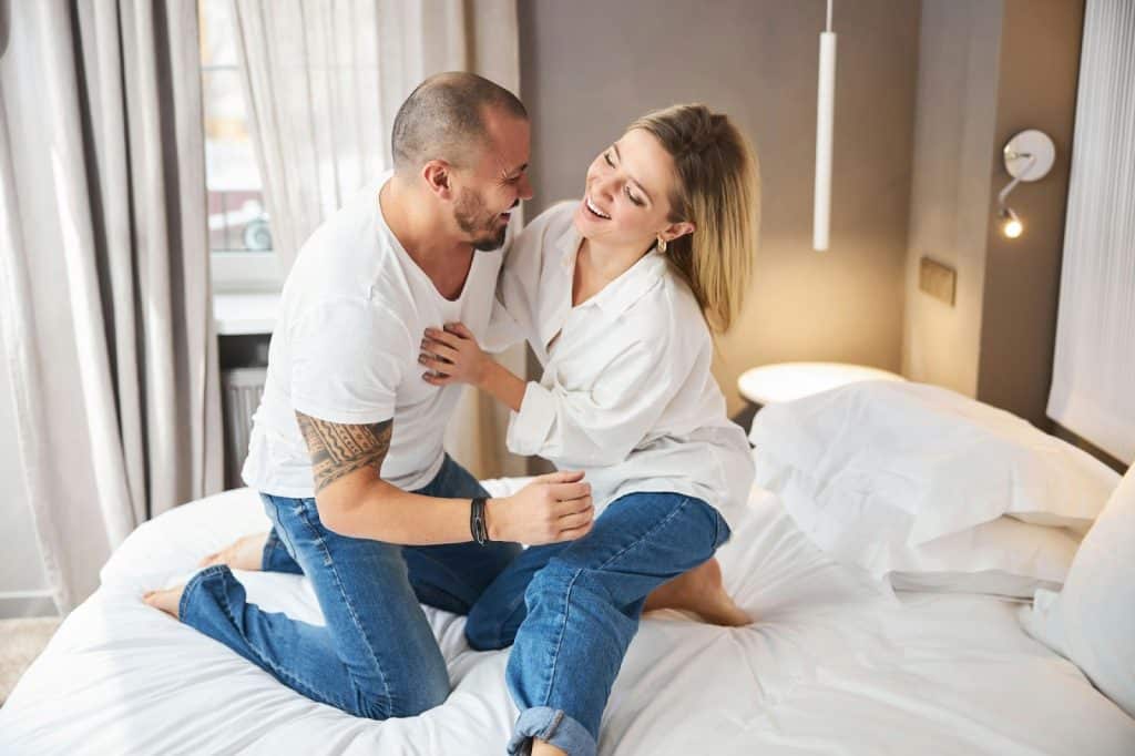 A man and woman being playful while at the bed 