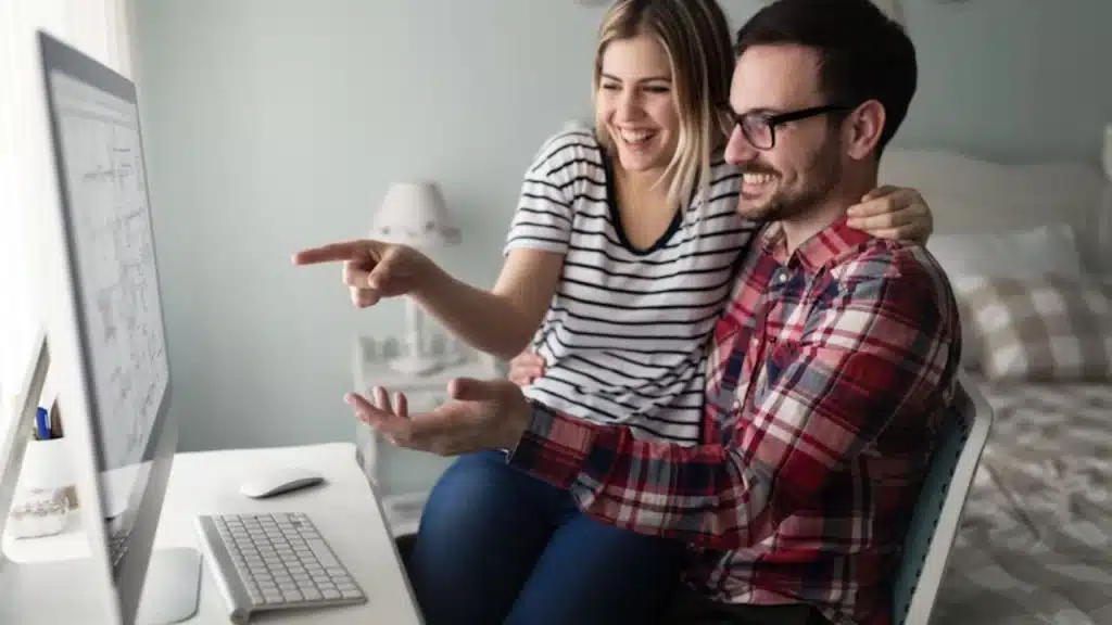 Man laughing with partner while looking at her project
