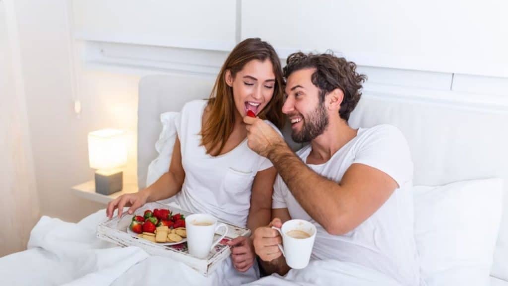 Man serving breakfast for his partner in bed