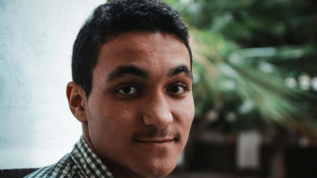 A young man is looking at the camera with a slight smile.