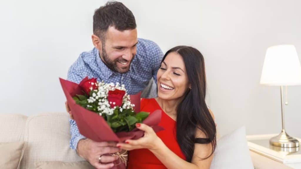 Man smiling while giving flowers to a woman