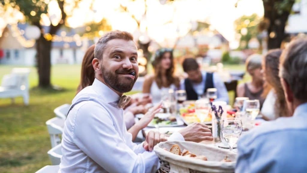 Man laughing with friends at outdoor dinner table