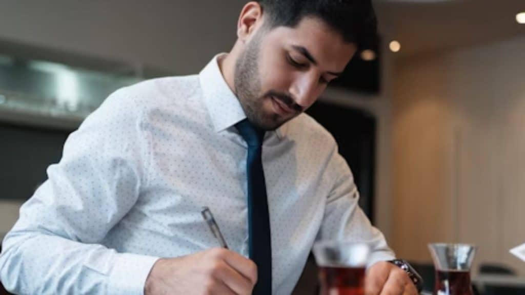 Man writing goals in notebook at desk