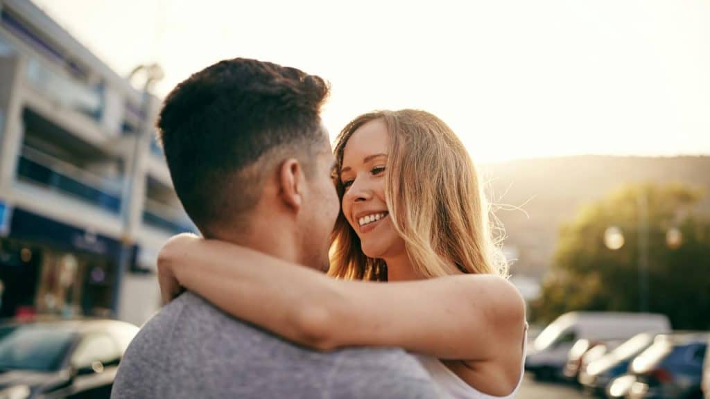 A young couple embracing outdoors at sunset.