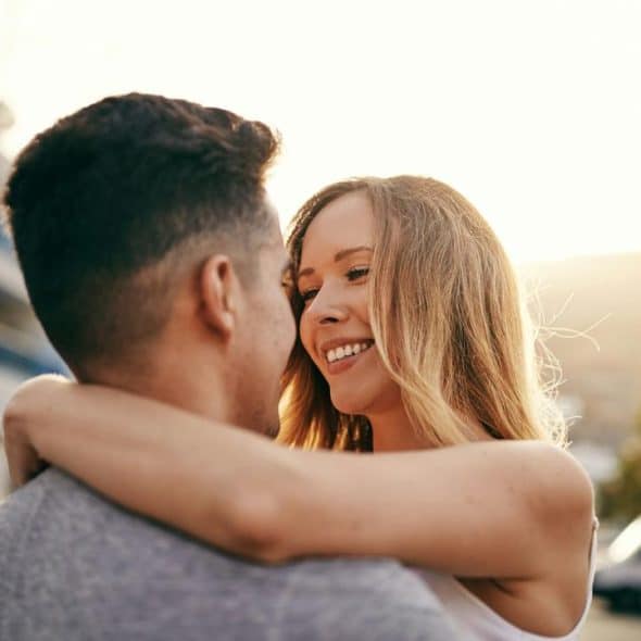 A young couple embracing outdoors at sunset.