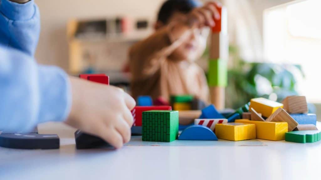 A close-up of children playing with colorful wooden building blocks.