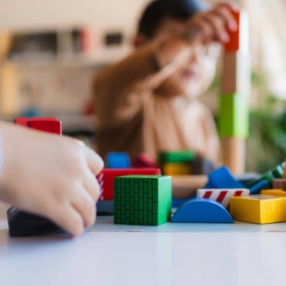 A close-up of children playing with colorful wooden building blocks.