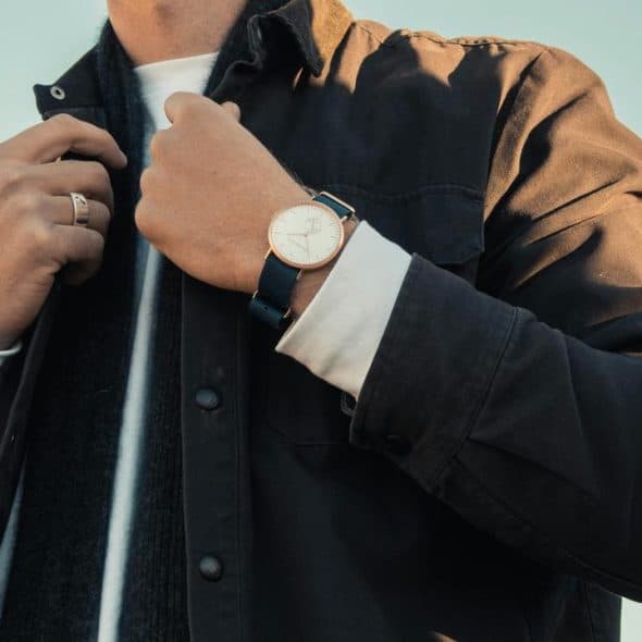 A man adjusting his jacket while wearing a wristwatch.