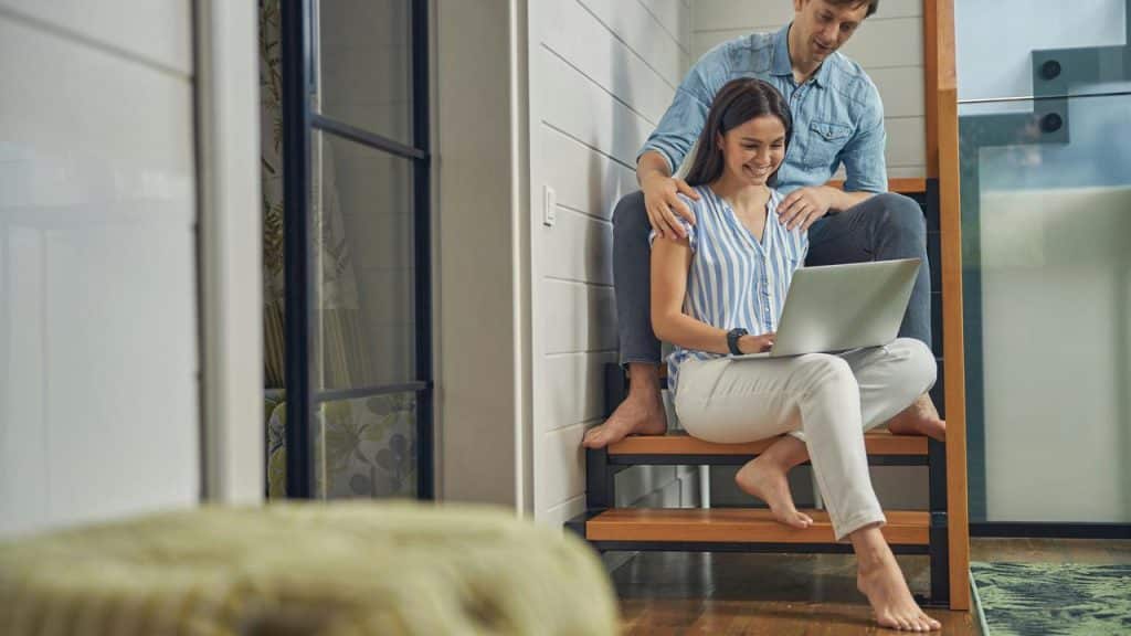 A couple sitting on stairs looking at a laptop together.
