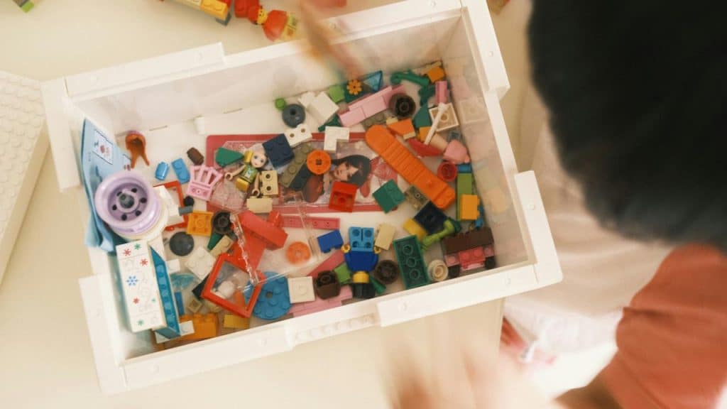 A child looking into a box of colorful LEGO pieces.