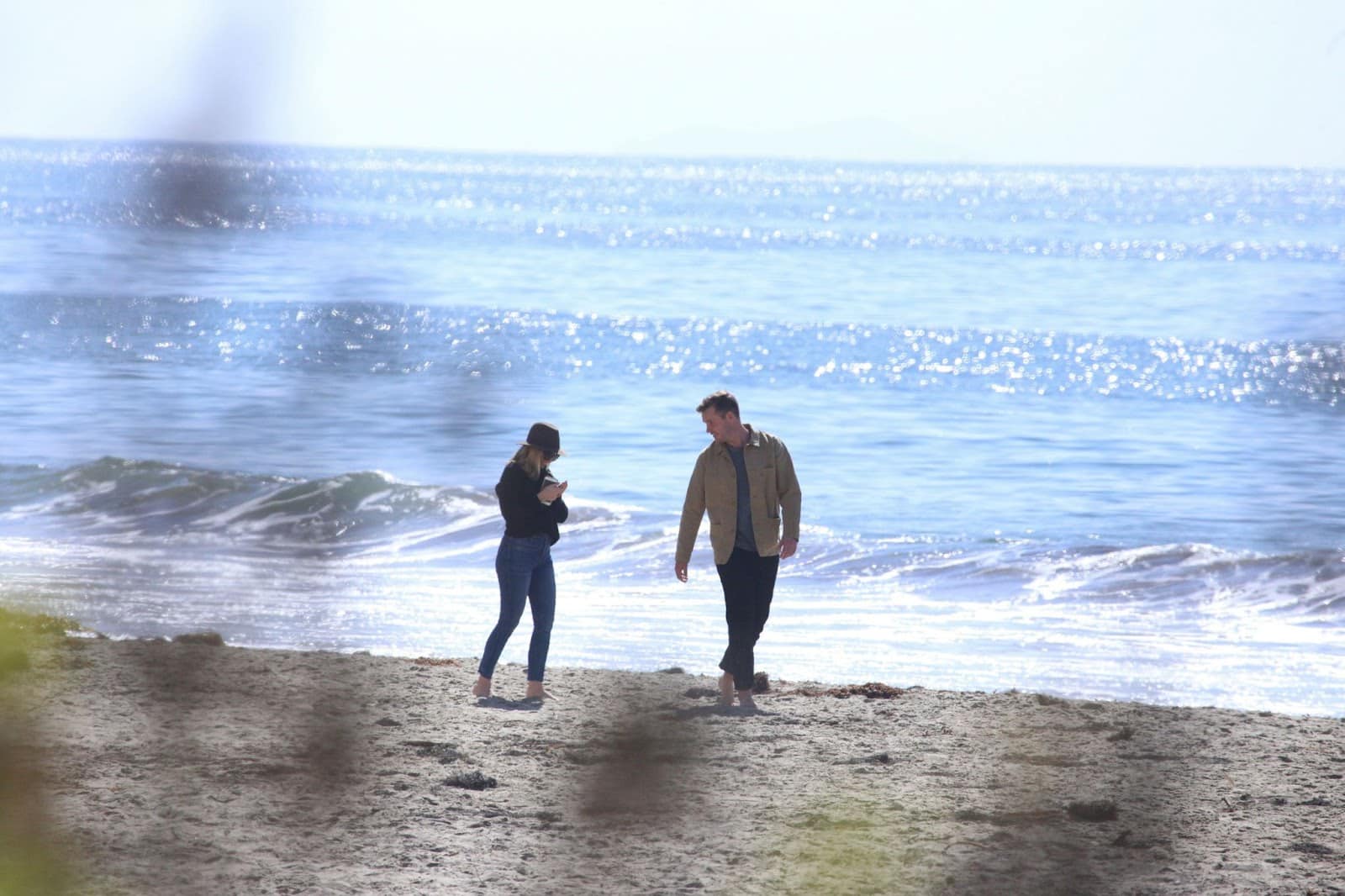 A man and woman walking at the beach.