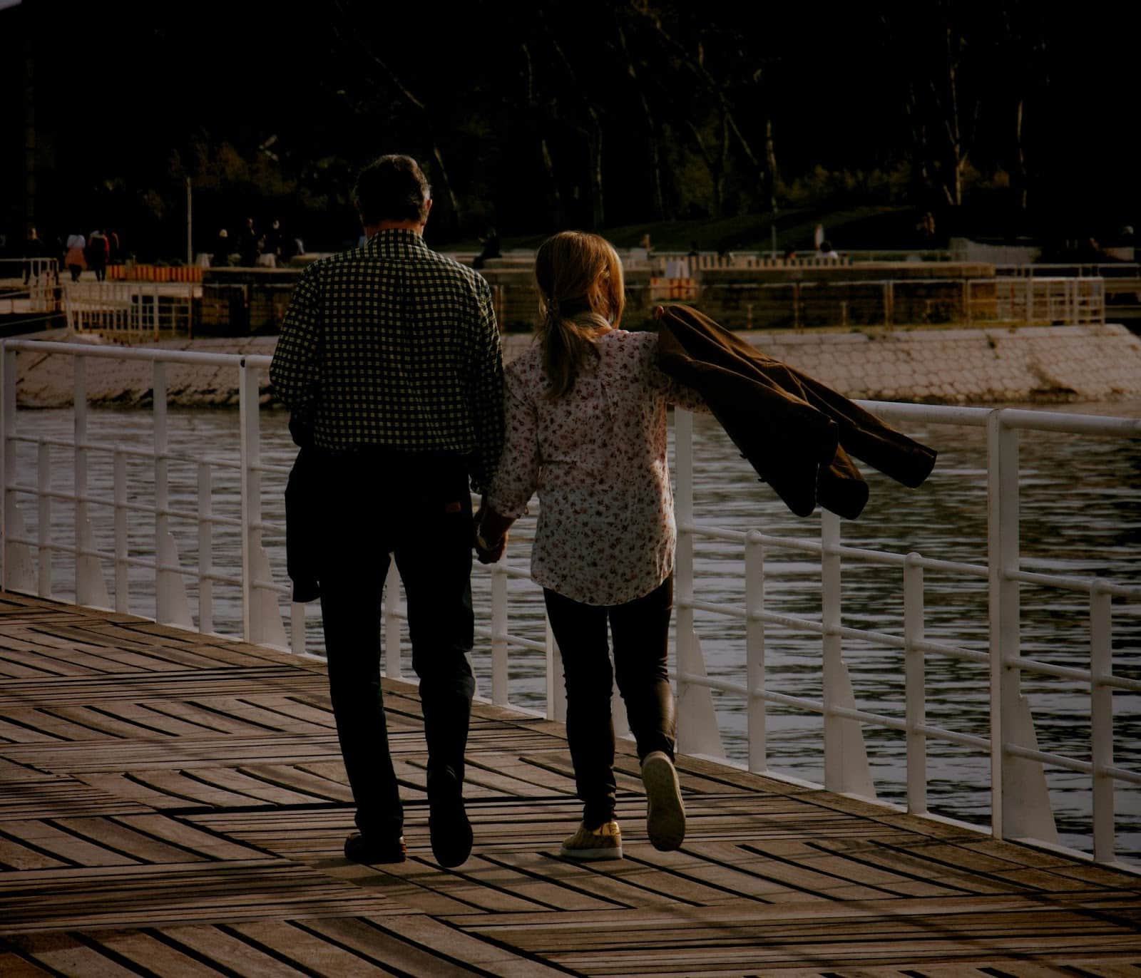 A man and woman walking on a dock.