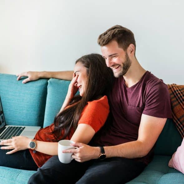 A woman busy with her laptop and a man watching her.