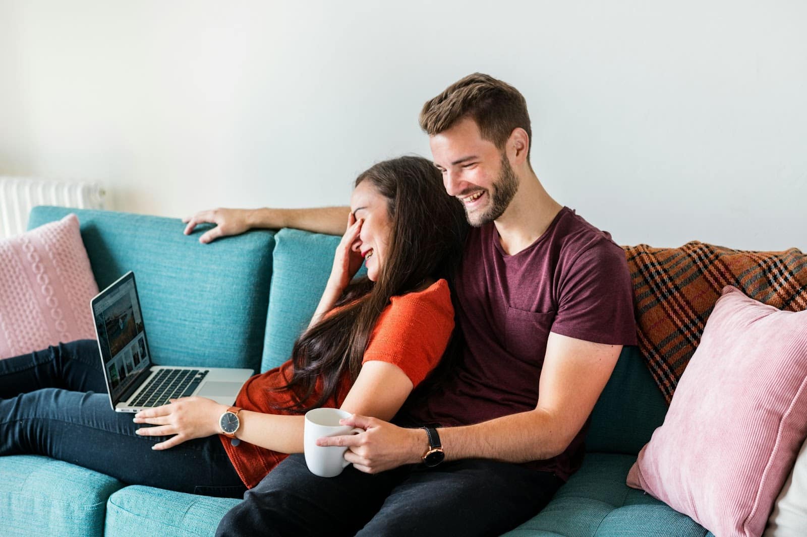 A woman busy with her laptop and a man watching her.