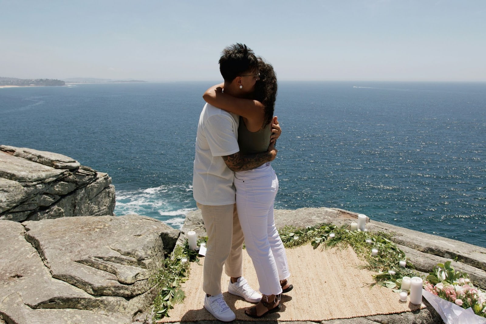 A man and woman hugging each other while at the beach.