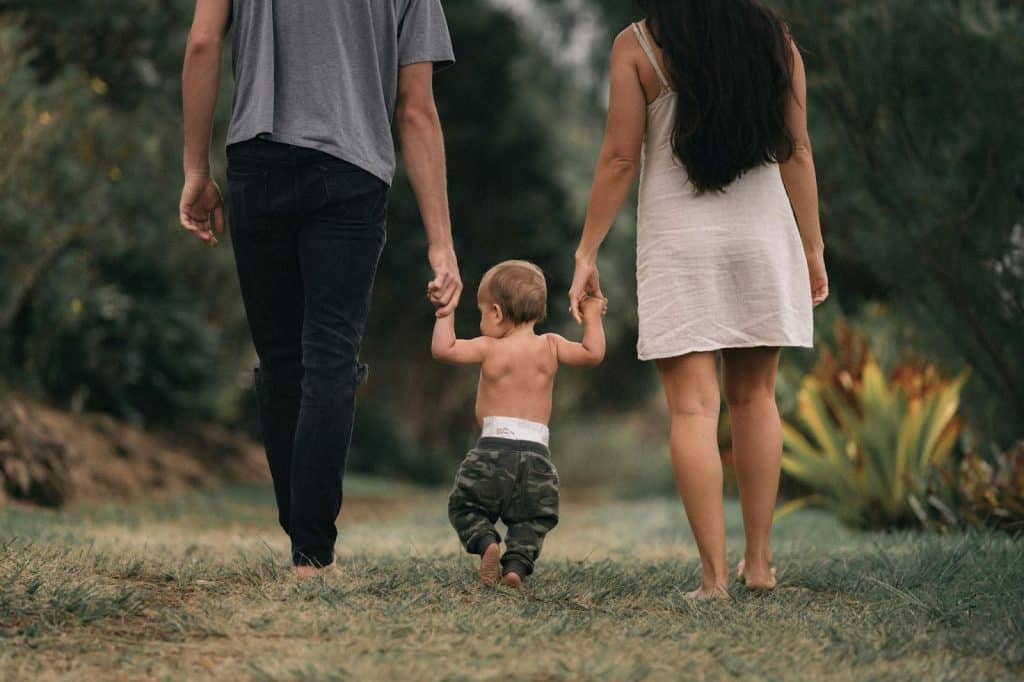 A man and woman walking holding their baby