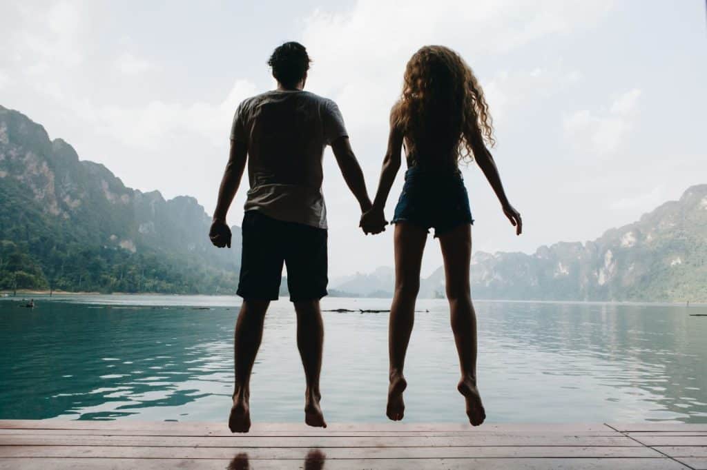 A man and woman jumping while holding hands