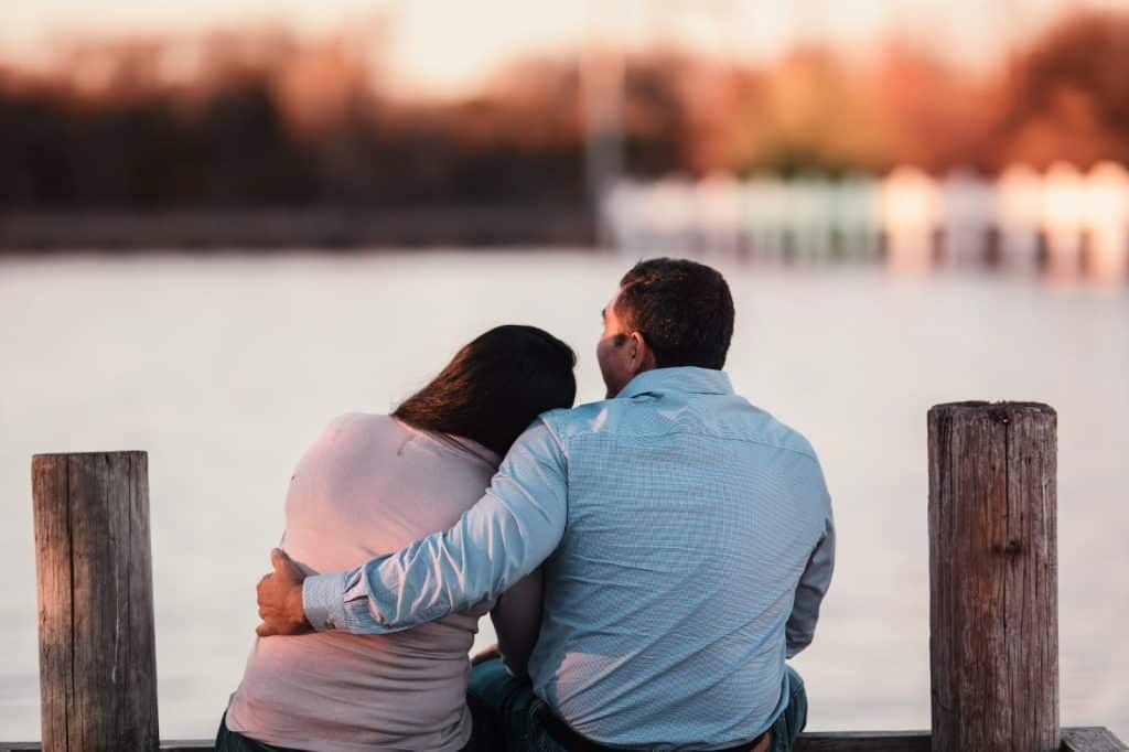 A man and woman sitting at the wooden deck